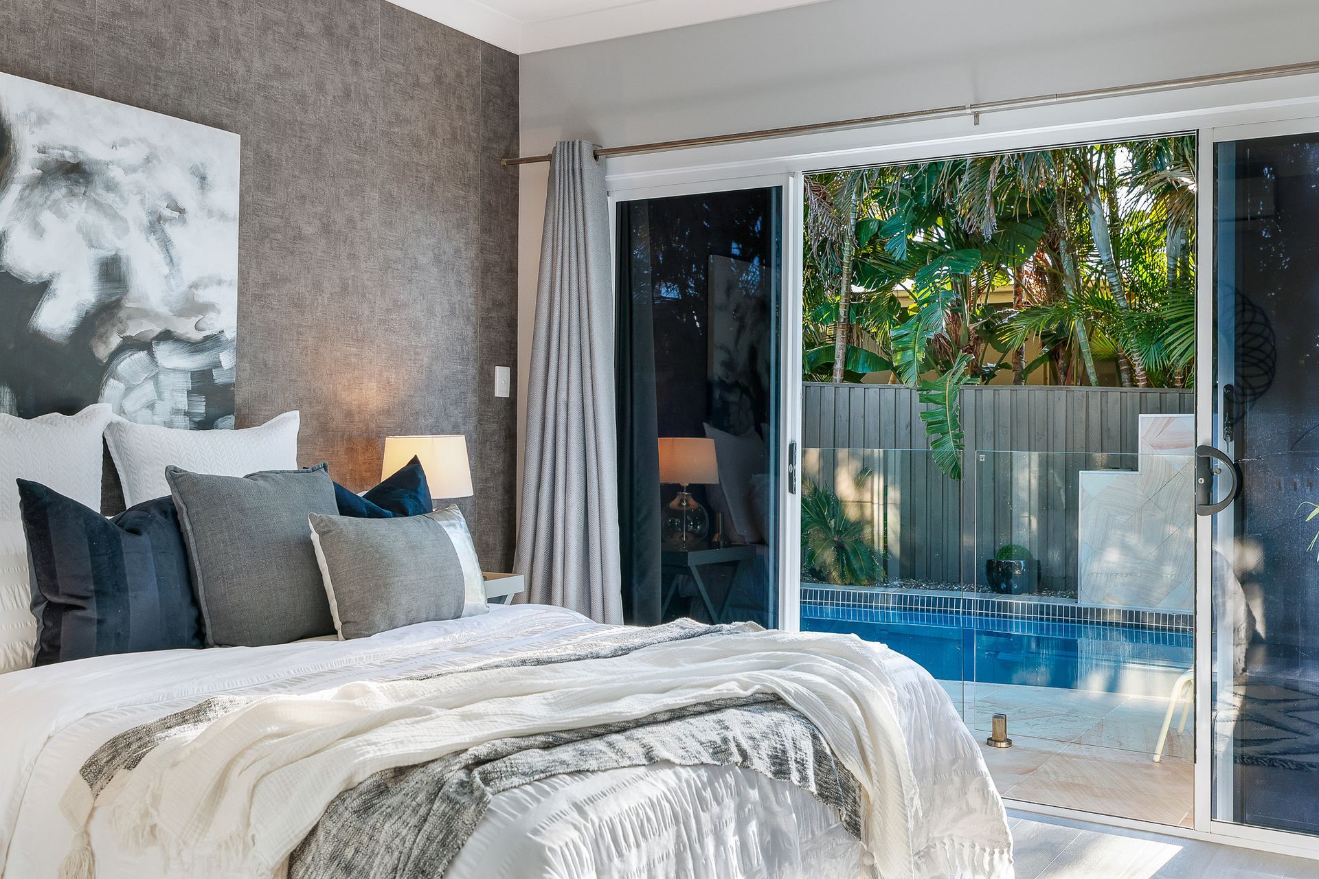 A bedroom with a sliding glass door leading to a pool.