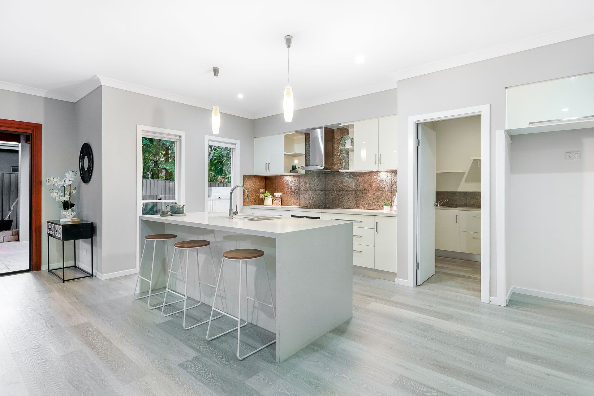 A kitchen with a large island and stools in a house.