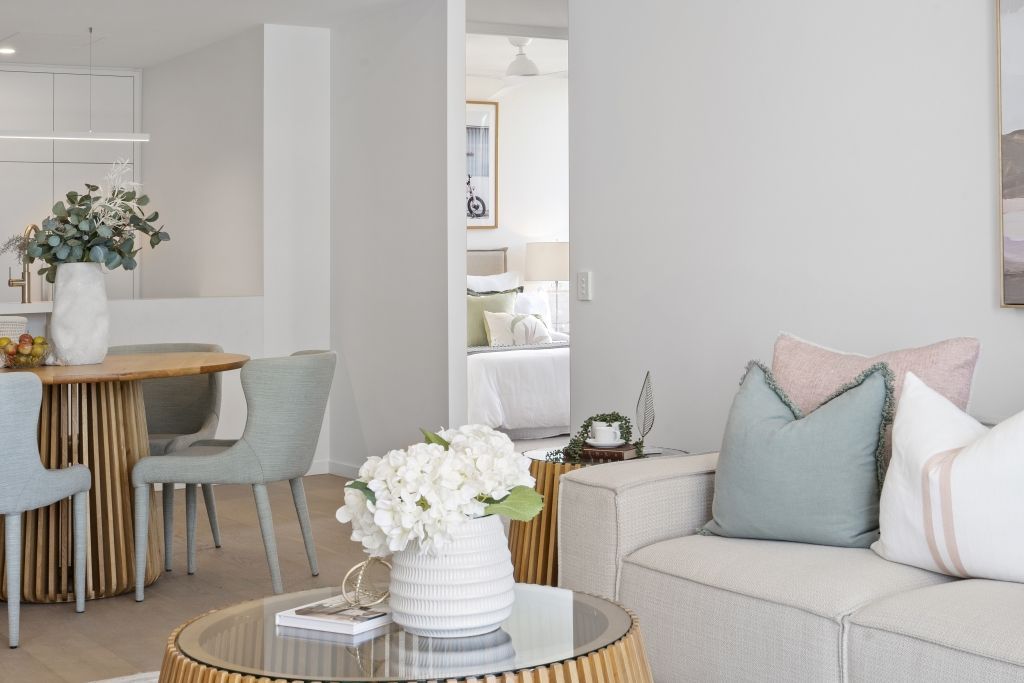 A living room with a couch , table , chairs and a vase of flowers.