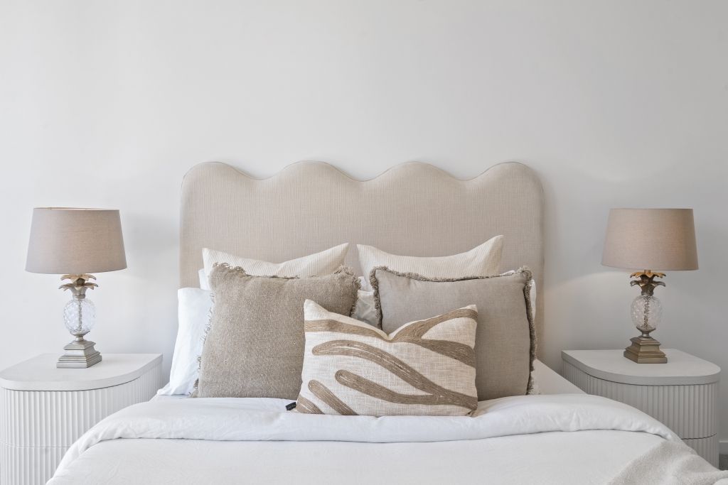 There is a bed with a headboard and pillows on it.