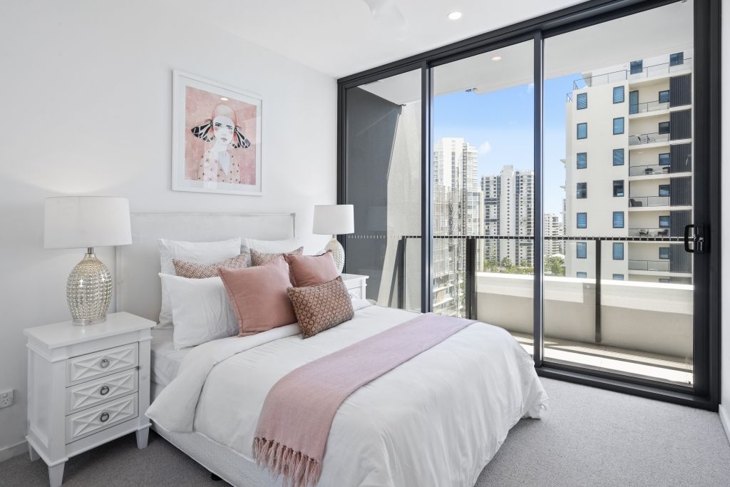 A bedroom with a bed , nightstand , and sliding glass doors leading to a balcony.