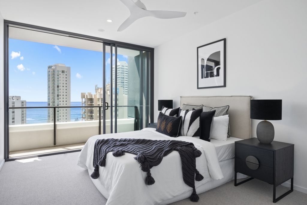 A bedroom with a large bed and a balcony overlooking the ocean