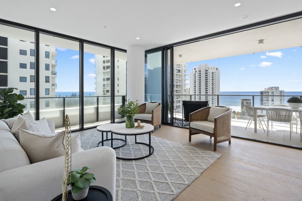 A living room with a couch , chairs , and a table with a view of the ocean.