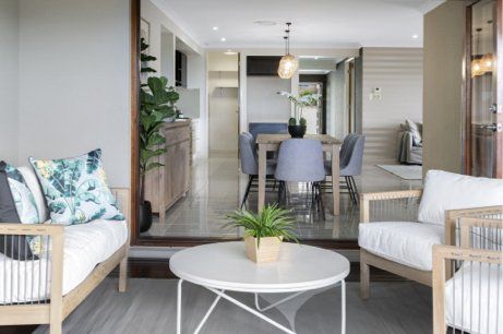 A living room with a couch , chairs , a table and a plant.