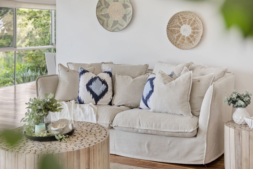 A living room with a white couch and wicker baskets on the wall.