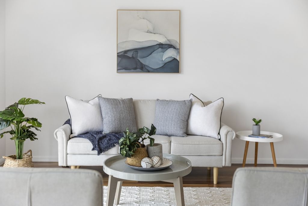 There is a painting on the wall above the couch in the living room.