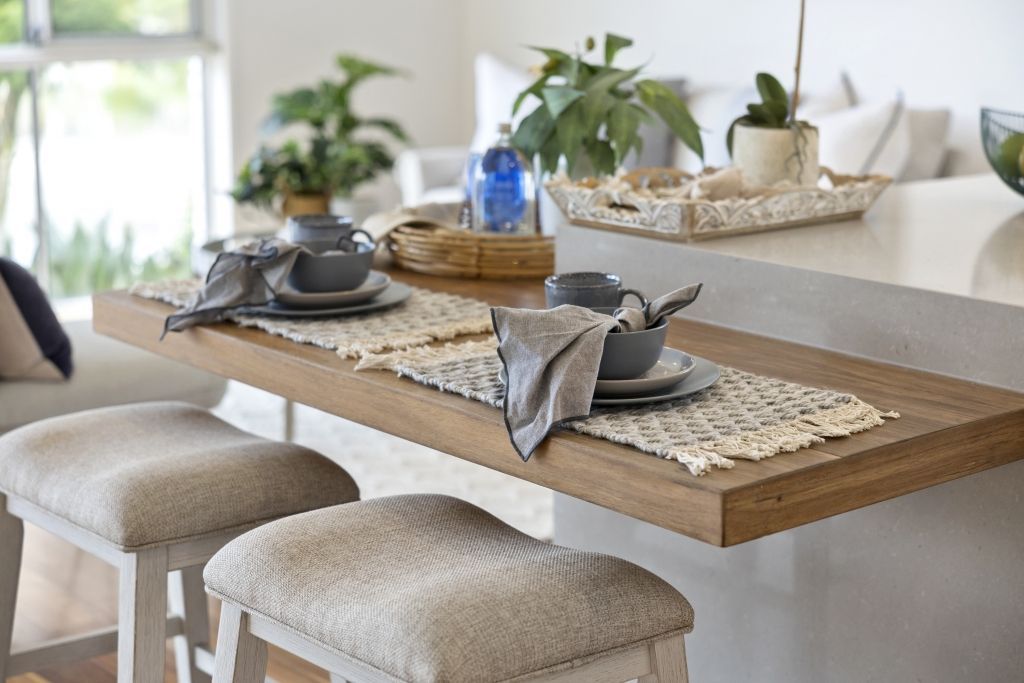 A dining room with a table and stools and plates on it.