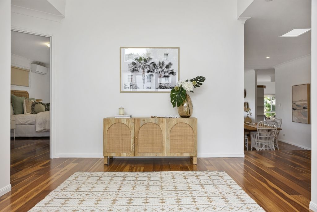 A living room with hardwood floors , a wicker dresser and a rug.