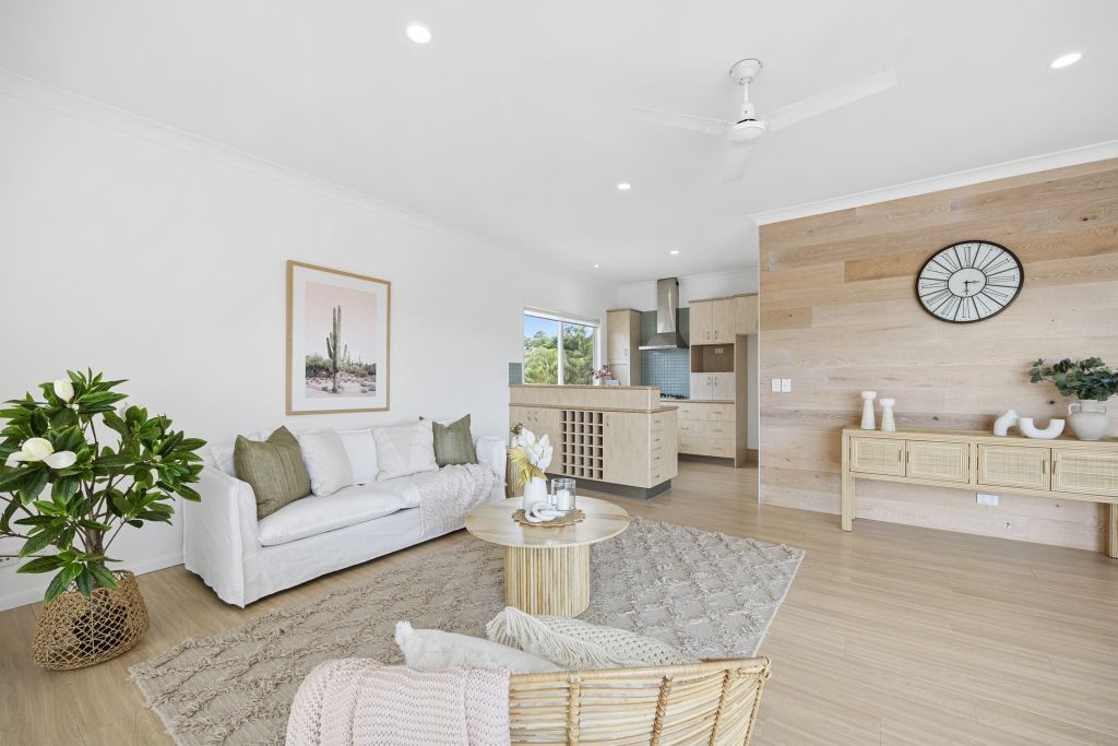 A living room with a couch , chair , table and a ceiling fan.
