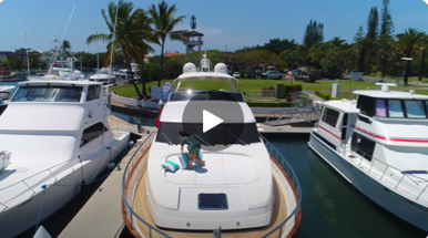 A group of boats are docked in a marina with a play button on the bottom of the screen.