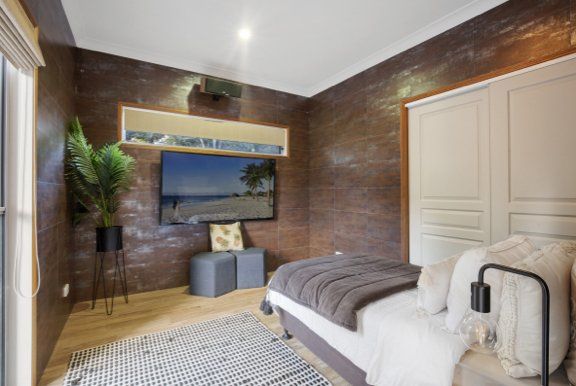 A bedroom with a bed and a television on the wall.