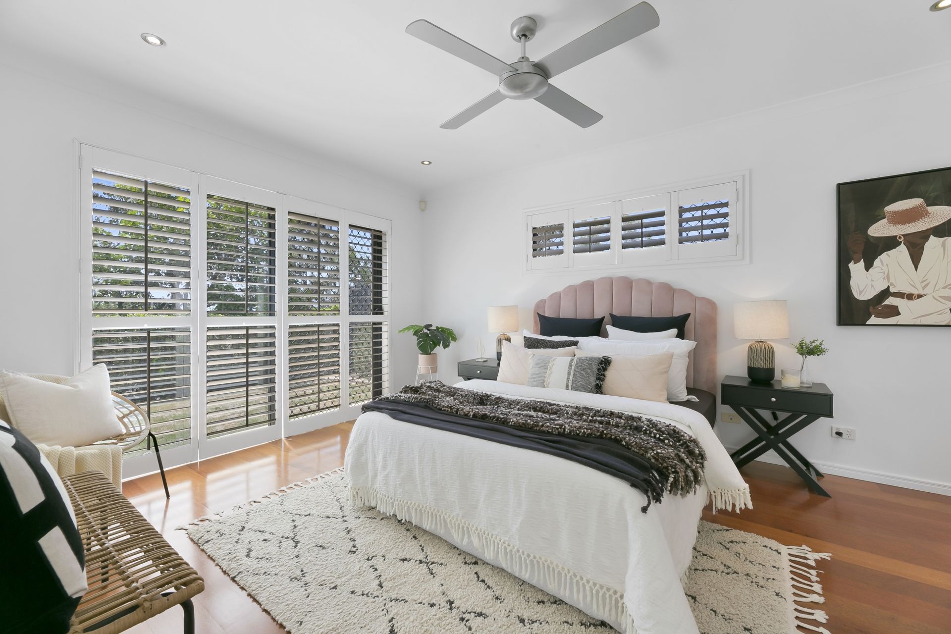 A bedroom with a large bed and a ceiling fan.