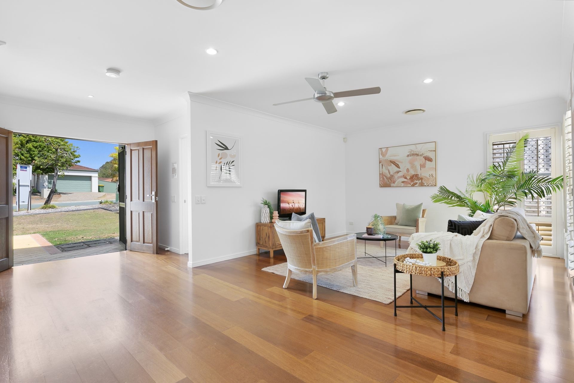 It is a living room with hardwood floors and a ceiling fan.