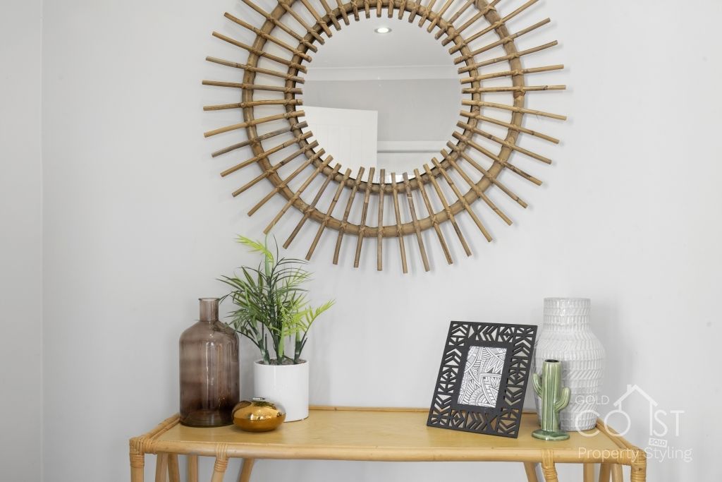 A wooden table with a mirror on the wall above it.