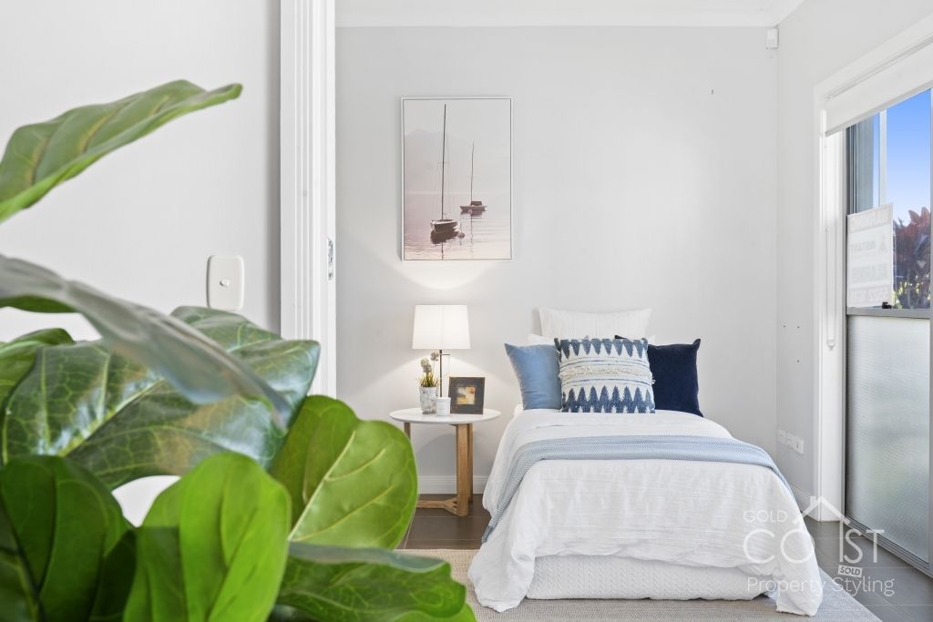 A bedroom with a bed and a plant in the foreground.
