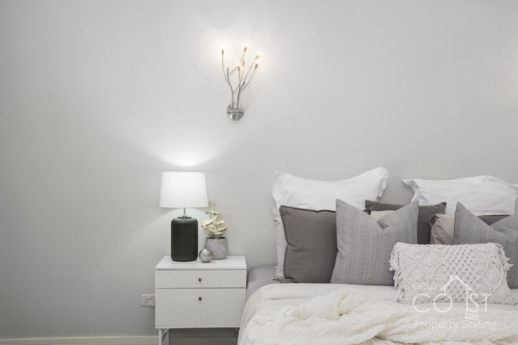 A bedroom with a bed , nightstand , lamp and white walls.
