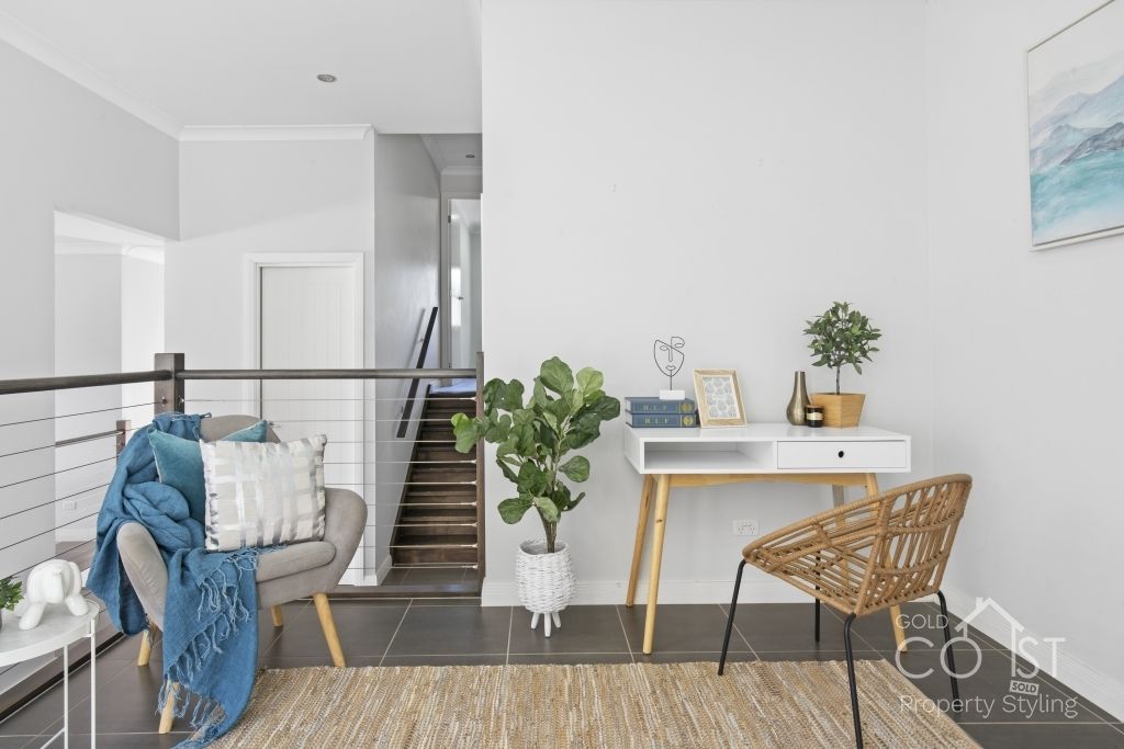 A living room with a desk , chair and stairs.