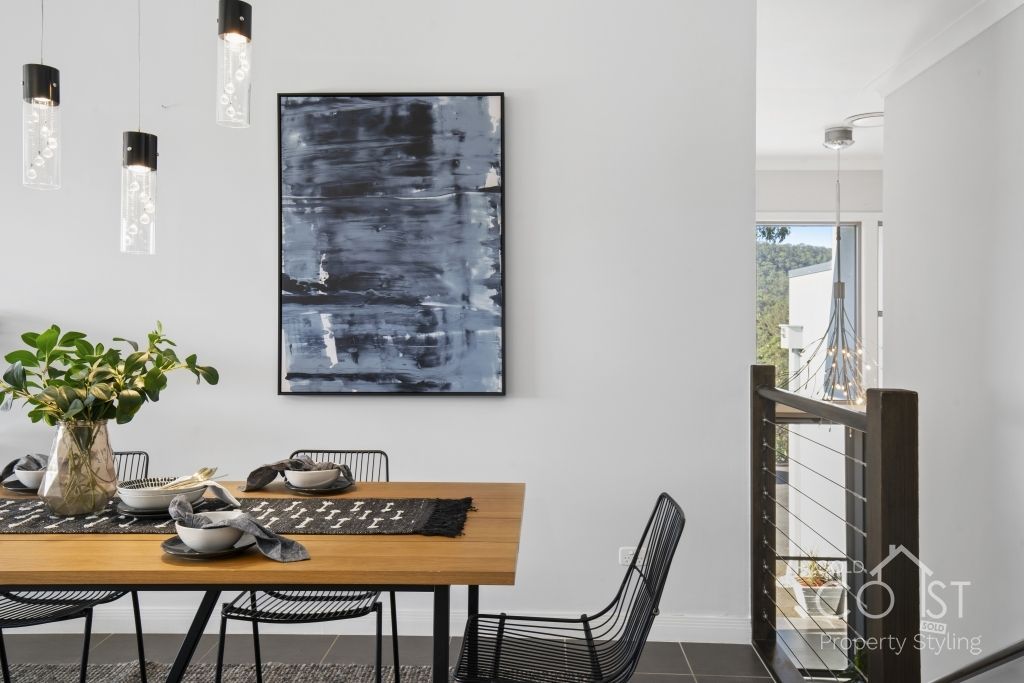 A dining room with a table and chairs and a painting on the wall.