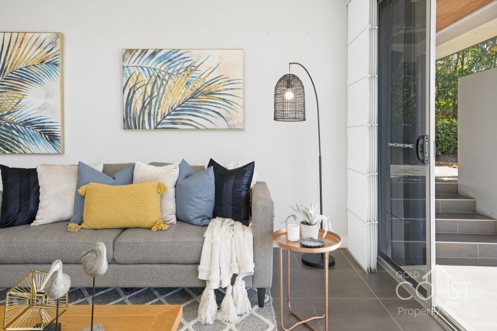 A living room with a couch , chair , table and paintings on the wall.