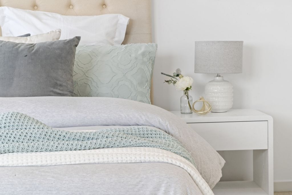 A bedroom with a bed , nightstand and lamp.
