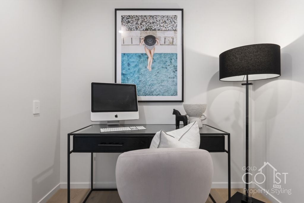 A room with a desk and chair and a picture on the wall