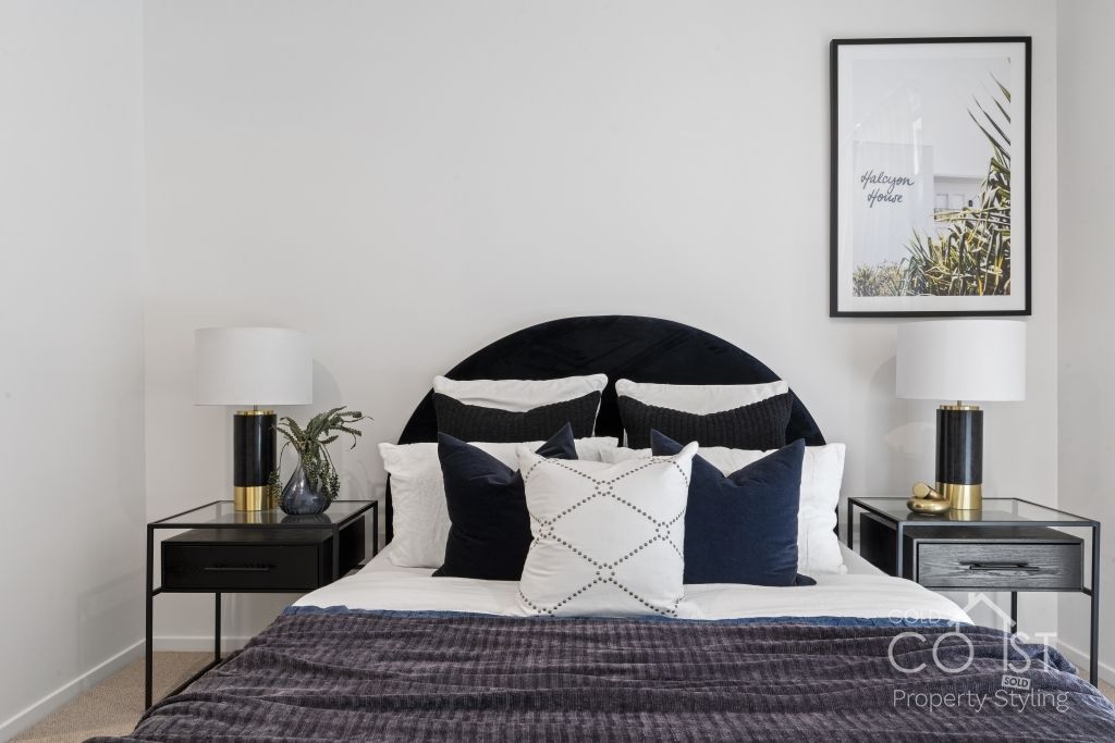 A bedroom with a bed , nightstands , lamps and a picture on the wall.
