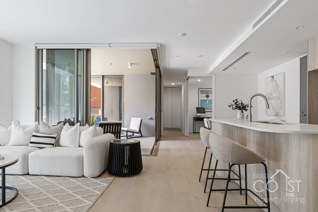 A living room with a couch , table , chairs and a kitchen.