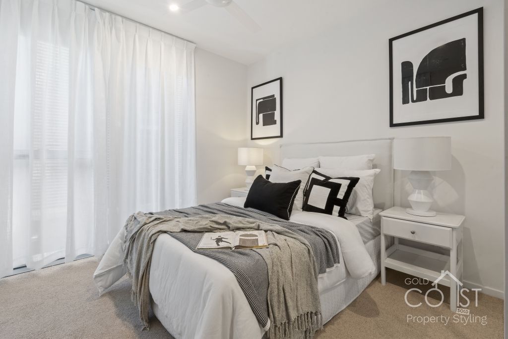 A bedroom with a bed , nightstand , lamps and curtains.