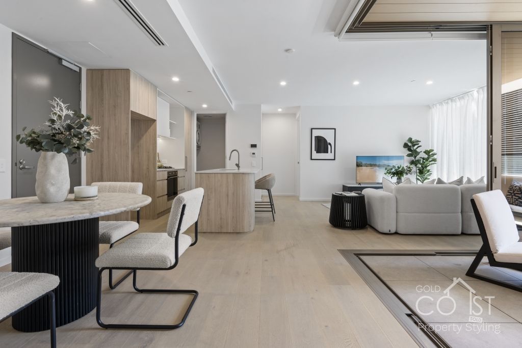 A living room with a dining table and chairs and a kitchen.