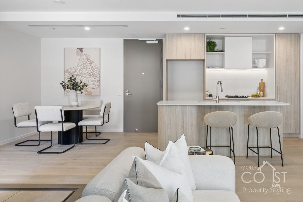 A living room with a couch , chairs , a table and a kitchen.