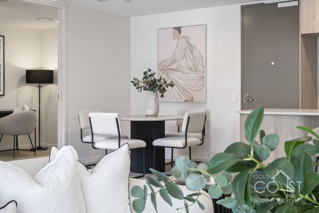 A living room with a table and chairs and a painting on the wall.