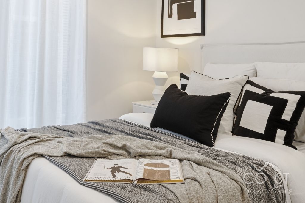 A bedroom with a bed , pillows , a lamp and a book on the bed.