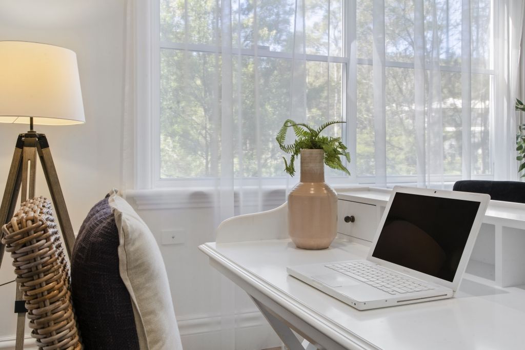 A laptop computer is sitting on a white desk in a living room.