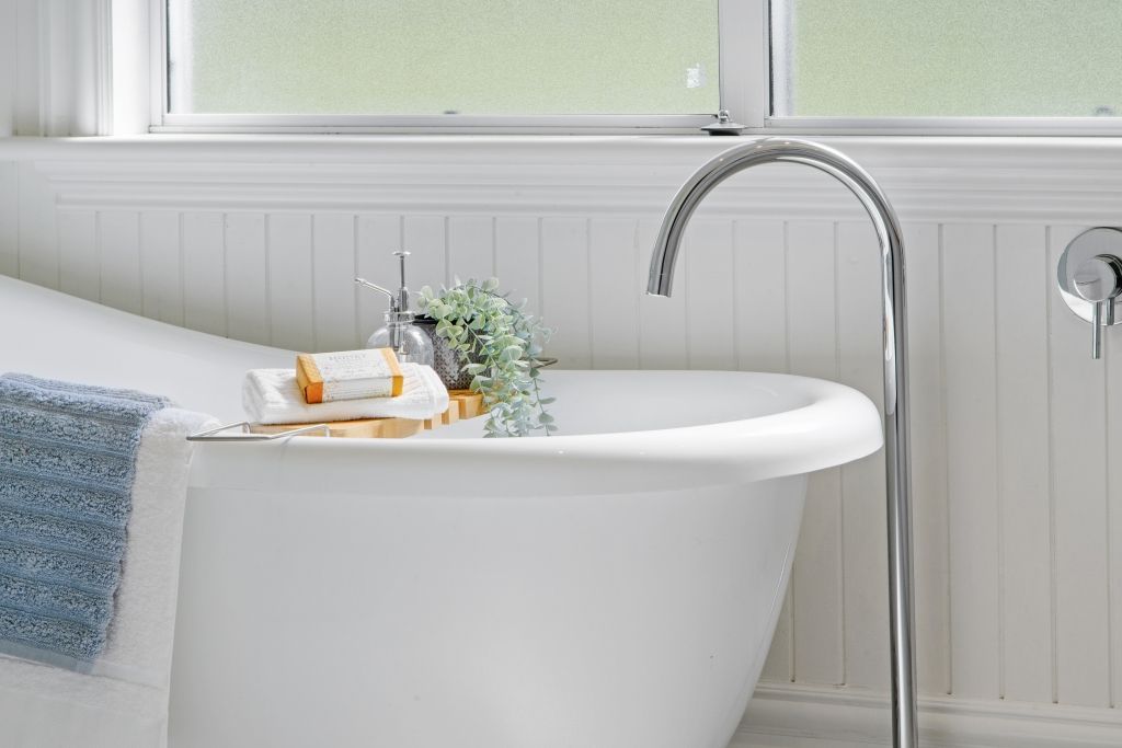 There is a bathtub in the bathroom next to a window.