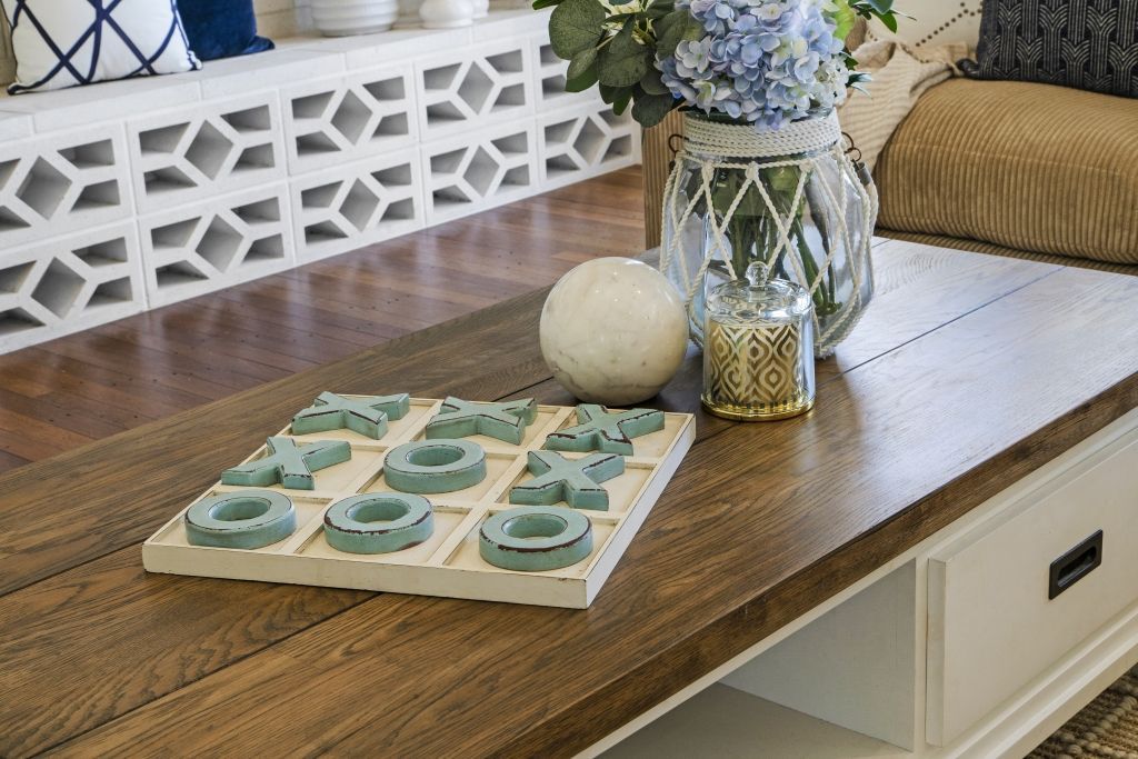 A wooden table with a tic tac toe game on it in a living room.