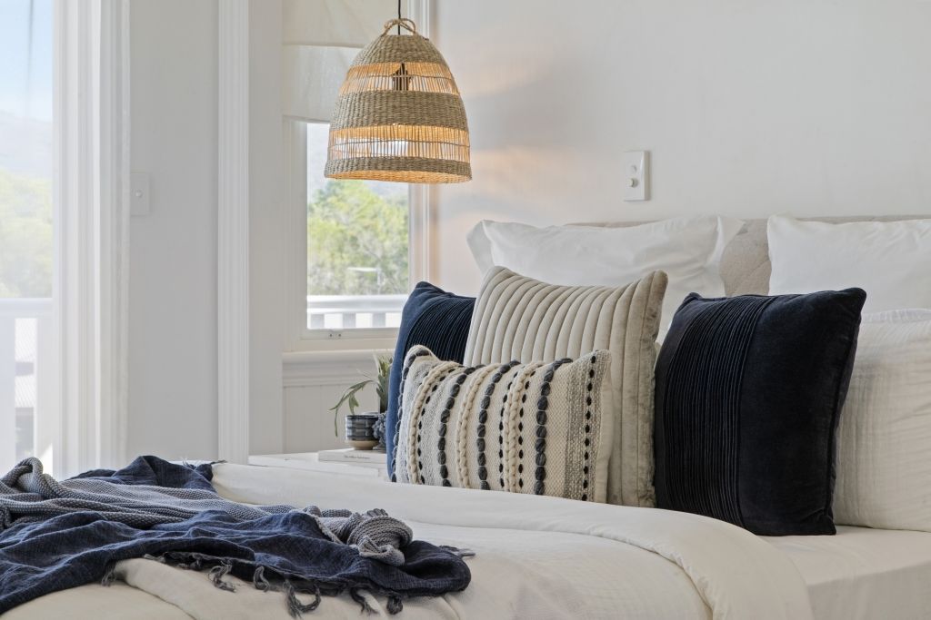 A bedroom with a bed , pillows , a lamp and a window.