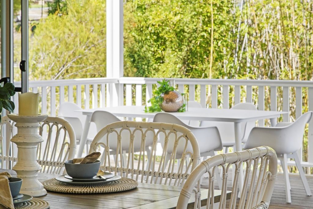 A dining room with a table and chairs on a porch.
