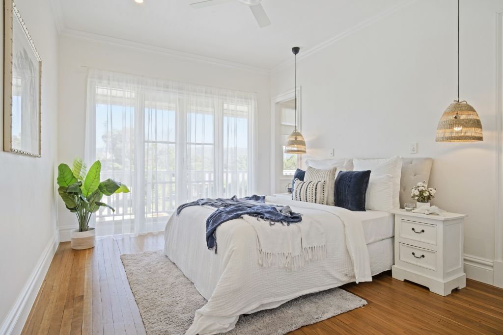 A bedroom with a large bed , two nightstands , and a ceiling fan.