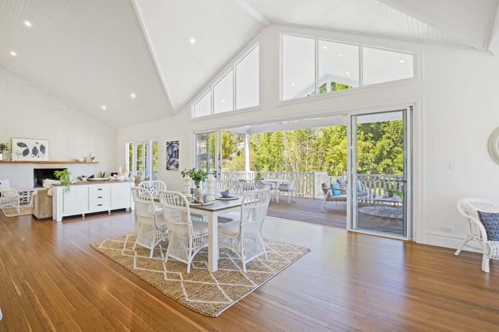 A living room with a dining table and chairs and a large window.