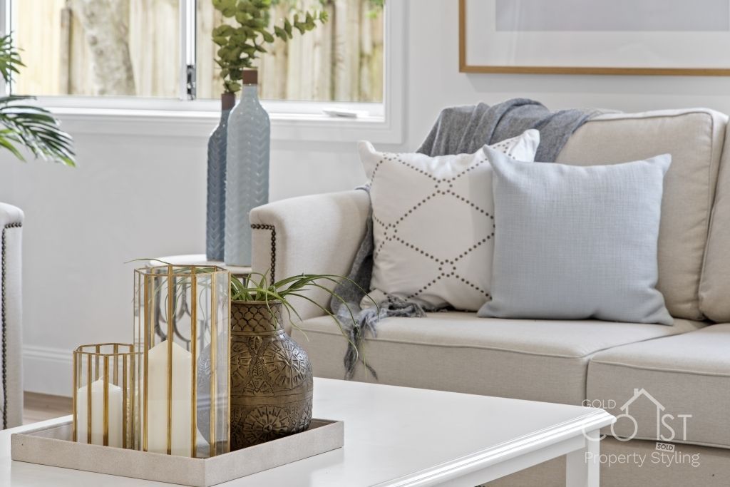 A living room with a couch , coffee table , vases and candles.