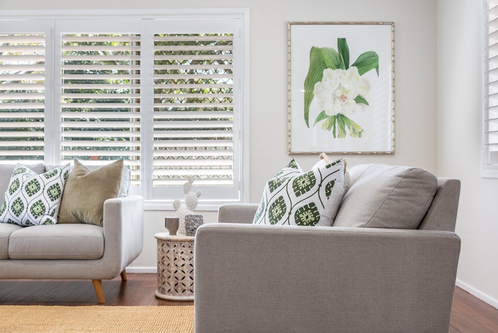 A living room with a couch , chair , table and shutters.