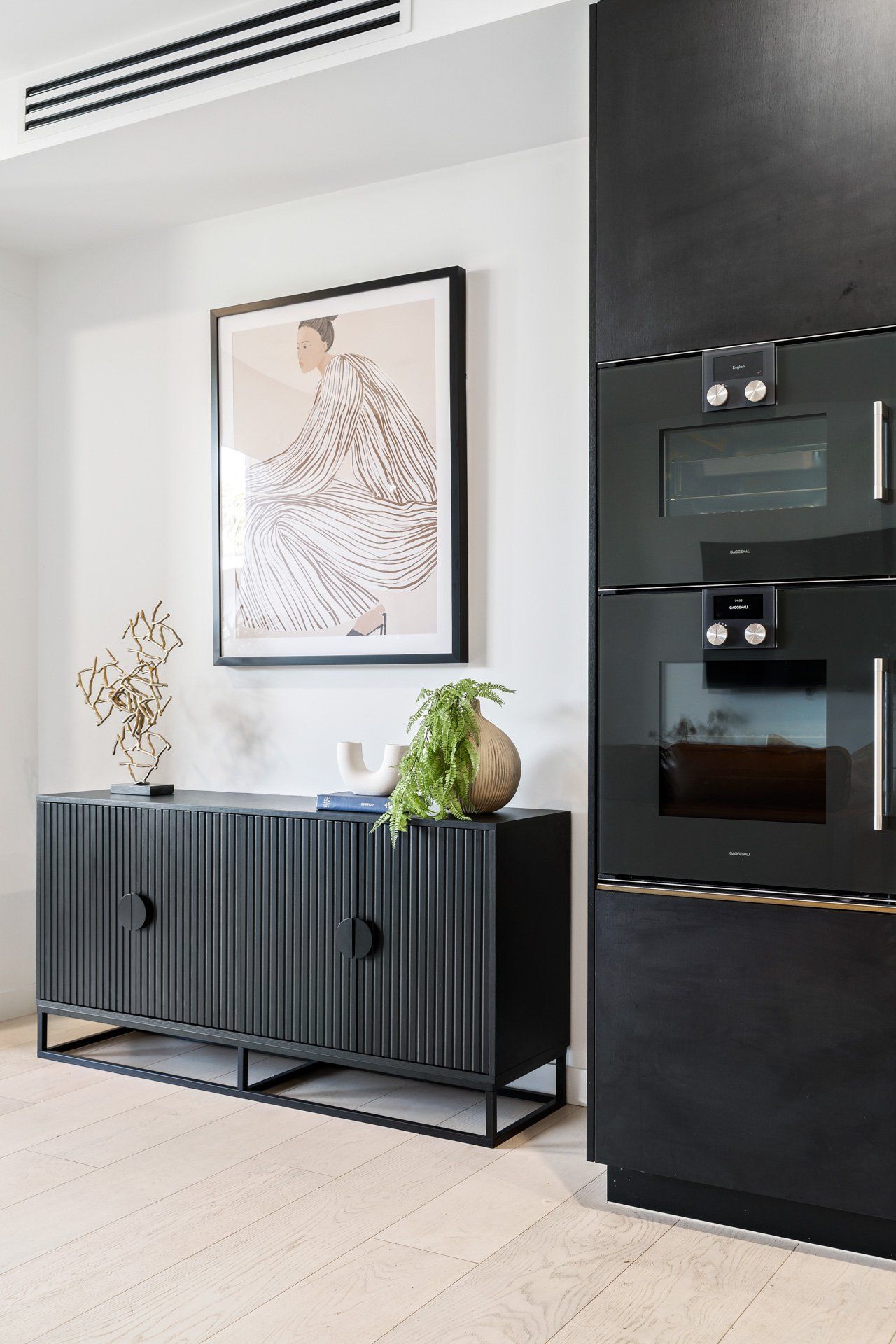 A kitchen with a black cabinet , black appliances , and a painting on the wall.