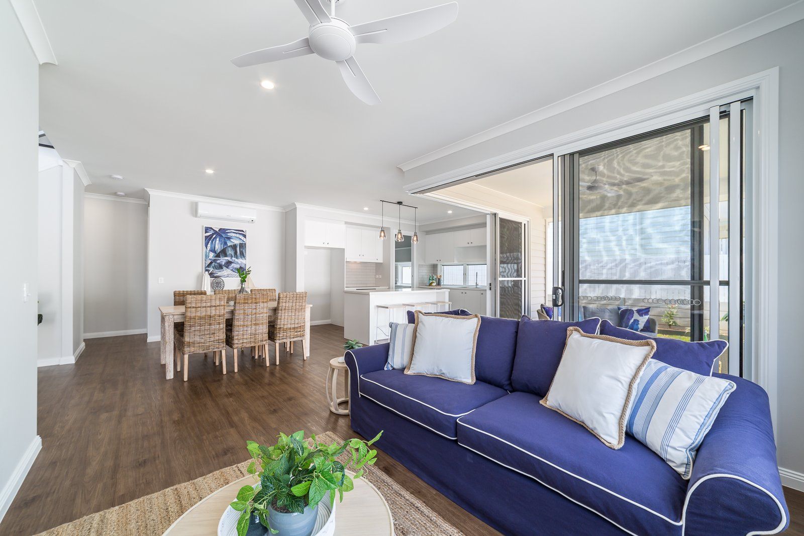 A living room with a blue couch and a ceiling fan.