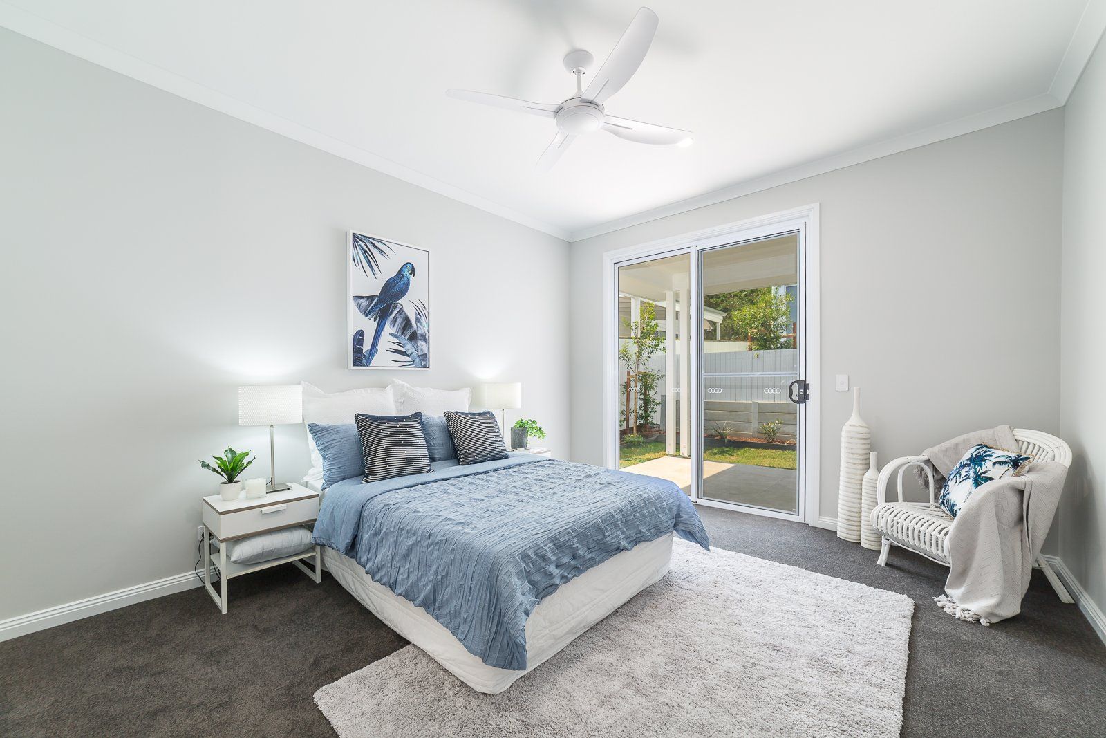 A bedroom with a bed , nightstand , chair and sliding glass doors.
