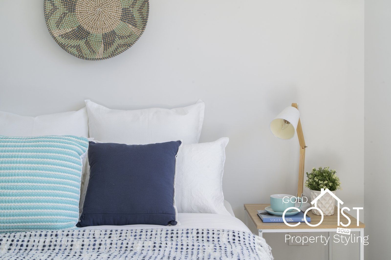 A bedroom with a bed , nightstand , lamp and pillows.