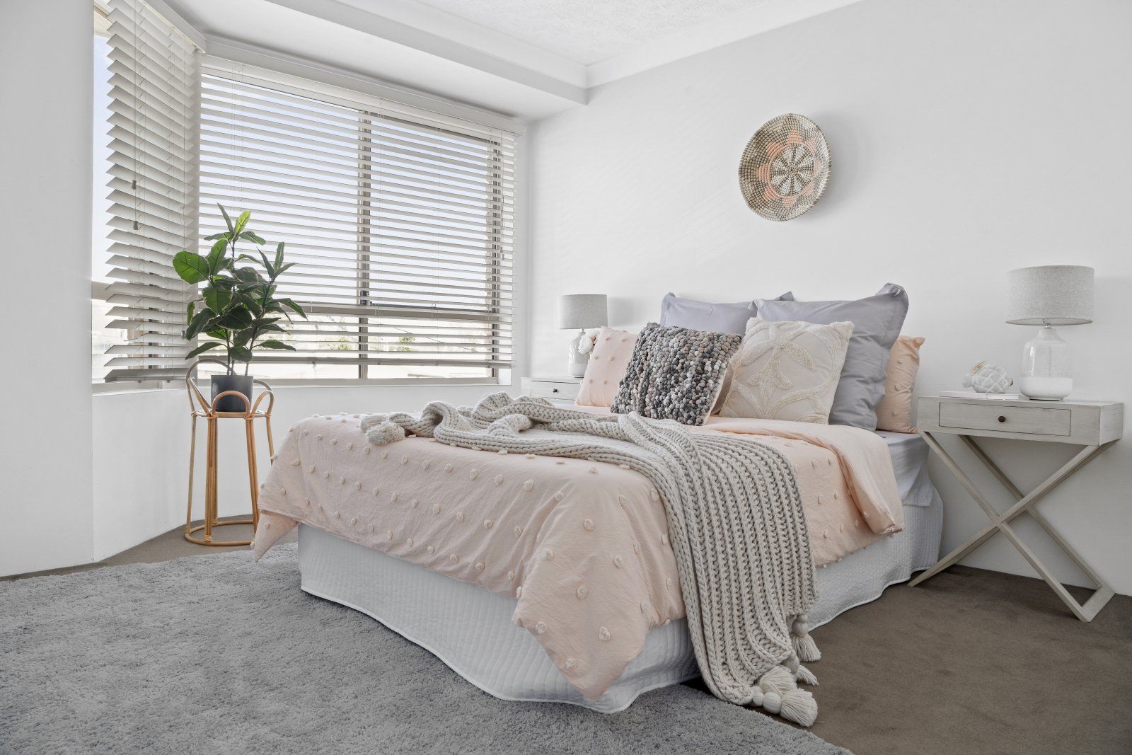 A bedroom with a bed , nightstand , lamps and a window.