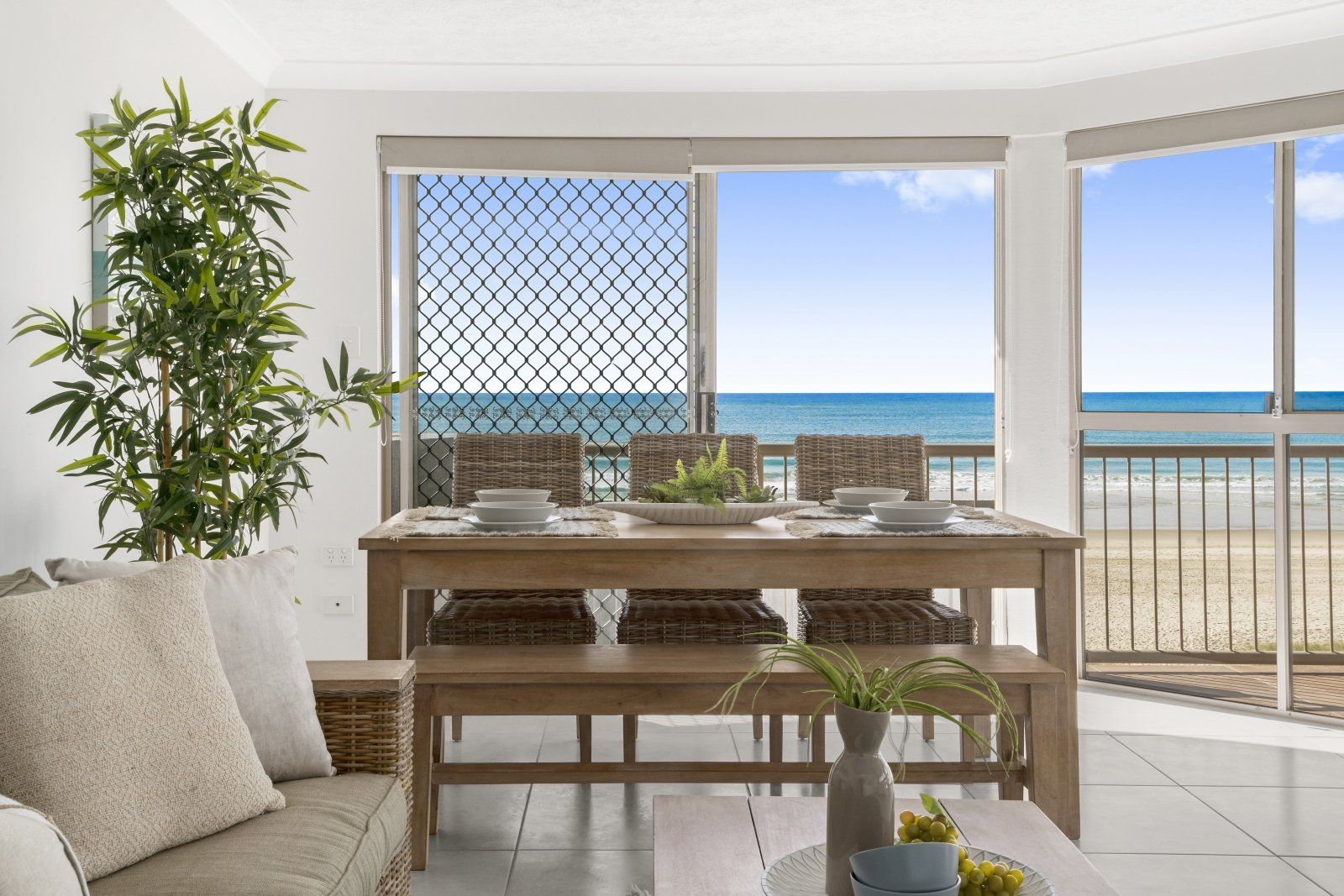 A living room with a couch , table and chairs and a view of the ocean.