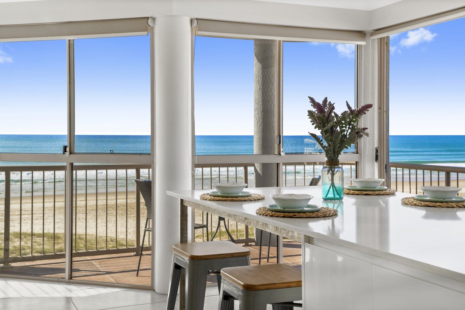 A dining room with a table and chairs and a view of the ocean.