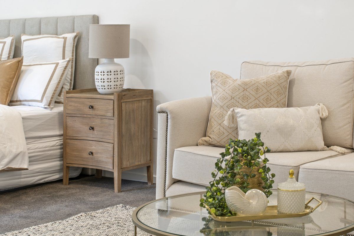 A living room with a couch , coffee table , nightstand and bed.