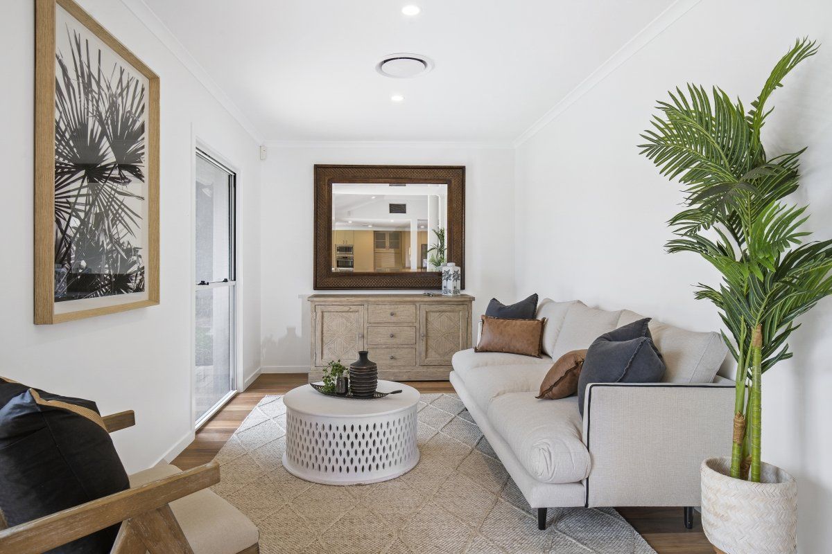 A living room with a couch , chair , coffee table and mirror.